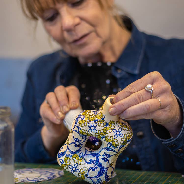 Lisette Boer brengt de decoupage lijm aan op het beeldje, zodat deze een mooi blauw patroon krijgt.