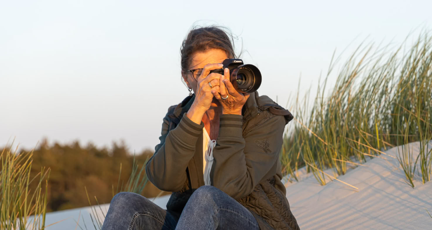 Francis Meinster neemt een foto op een duin aan het strand.