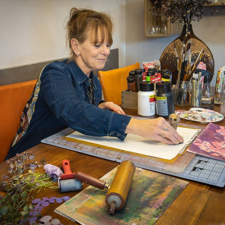 Lisette Boer stampt het papier aan om een nieuwe monoprint te maken.