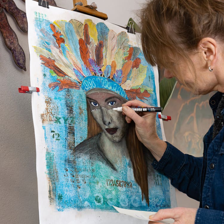 Lisette Boer tekent met de hand de laatste details op een monoprint van een kunstwerk met als onderwerp een indiaanse vrouw.
