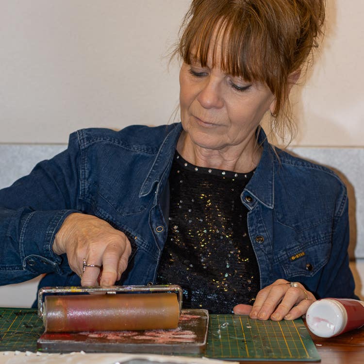 Lisette Boer bezig met een roller op een door haar gemaakte monoprint.
