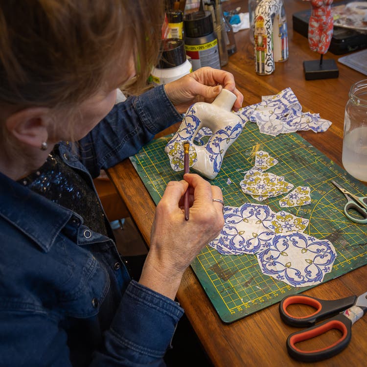 Decoupage van Lisette Boer. Dit is een techniek waarbij afbeeldingen, papier of stof met een speciale lijmlak worden aangebracht op verschillende oppervlakken, zoals hout, glas, metaal of keramiek, en vervolgens worden afgewerkt met een laagje decoupagelijm.